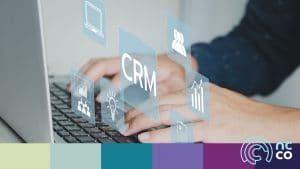 Photo of hands typing on a laptop keyboard with graphics relating to CRM scattered on top of the photo